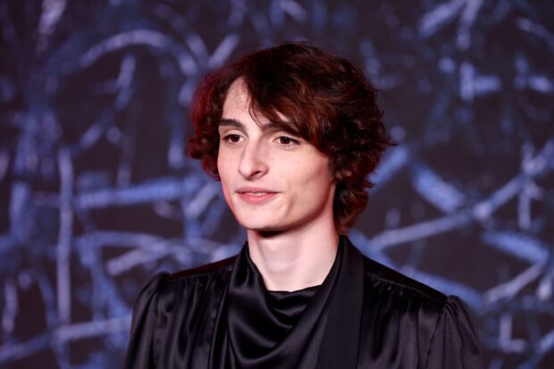 Finn Wolfhard wearing a black outfit with a blurred dark background, 2K Desktop Wallpaper