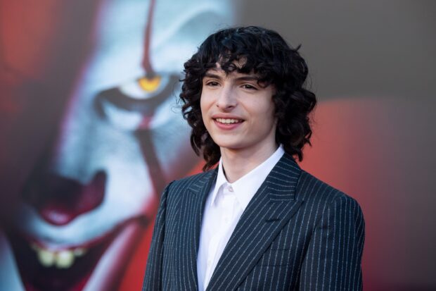 Finn Wolfhard is smiling while dressed in a striped suit at a movie premiere, 2K Desktop Wallpaper