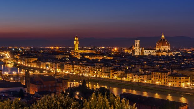 The Florence cityscape glows warmly with historic buildings and river reflections at dusk, 4K Desktop Wallpaper