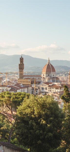 A scenic view of Florence showcasing its iconic dome and towers with greenery in the foreground, 2K Mobile Wallpaper