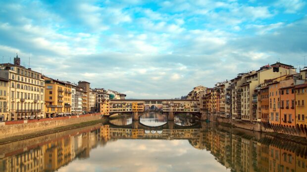 The historic buildings along the river and the famous bridge are reflected in calm water in Florence, 4K Desktop Wallpaper