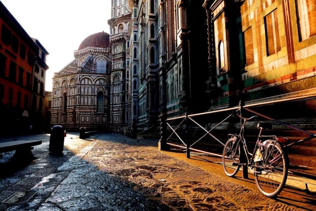 A bicycle standing beside an ornate building in Florence captures the warm sunset light in the quiet street, HD Desktop Wallpaper