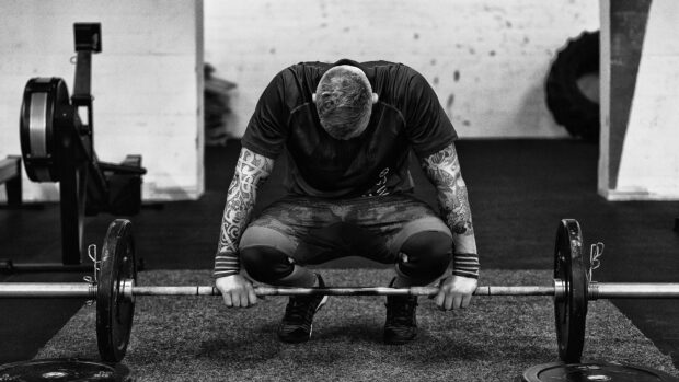 A crossfit athlete with tattooed arms is focused on lifting a barbell in the gym, HD Desktop Wallpaper