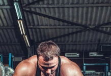 A muscular man grips the bar preparing for a powerlifting lift in the gym, 2K Phone Wallpaper