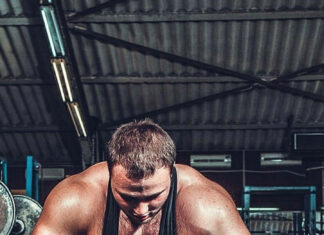A muscular man grips the bar preparing for a powerlifting lift in the gym, 2K Phone Wallpaper