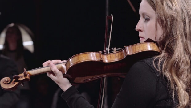 A woman is focused on playing the violin during a musical performance, 4K Desktop Wallpaper