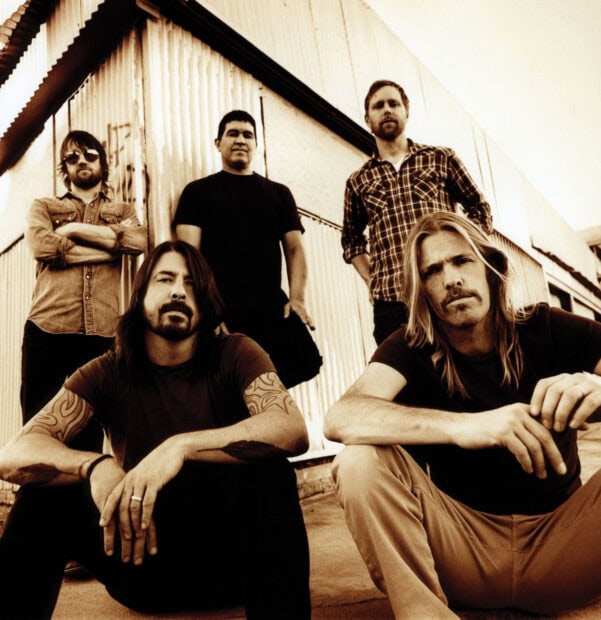 The Foo Fighters band poses together near a building in a sepia tone, HD Desktop Wallpaper