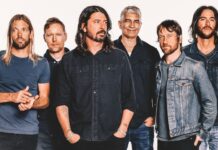 Fashionable male band members wearing denim and casual t-shirts against white background.
