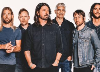 Fashionable male band members wearing denim and casual t-shirts against white background.