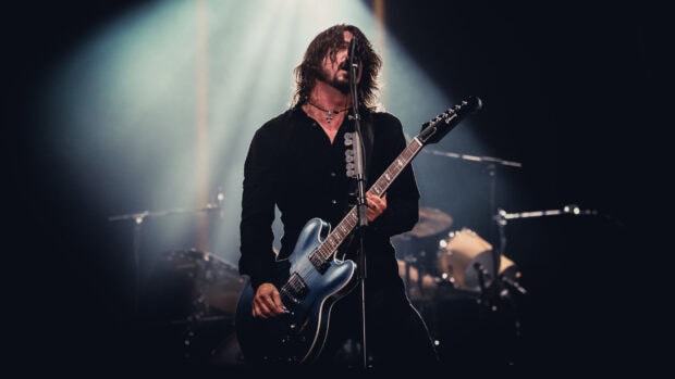 A musician from Foo Fighters is playing guitar on stage during a live concert, 2K Desktop Wallpaper
