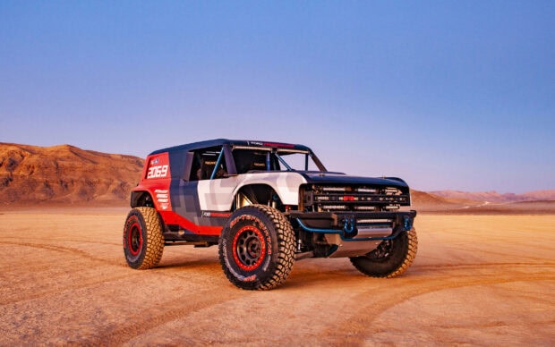 Ford Bronco off road vehicle parked on desert terrain with mountains in the background