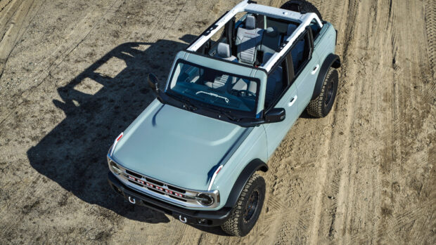 A high angle view of a Ford Bronco parked on a dirt surface with no roof on a sunny day