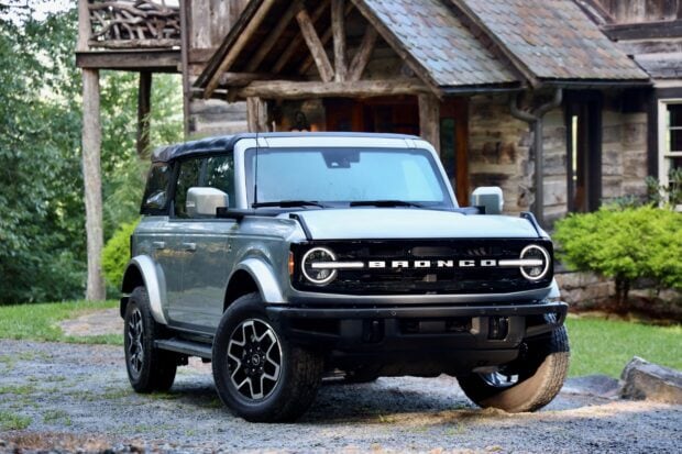 Silver Ford Bronco parked in front of a rustic wooden cabin