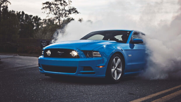 Blue Ford Mustang burning out on the road with smoke around the car