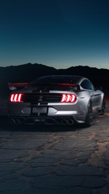 Rear view of Ford Mustang at dusk on cracked pavement with mountains in background