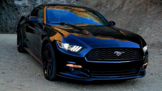 Black Ford Mustang with shiny surface parked on a dirt road