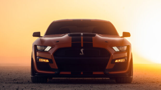 Ford Mustang car front view with racing stripes in a desert at sunset