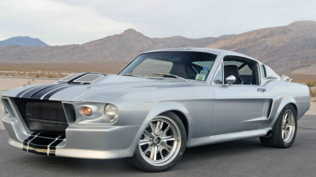 A classic Ford Mustang car parked on a desert road with mountains in the background
