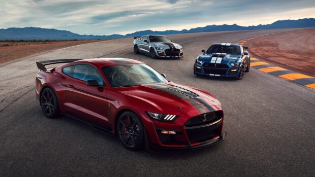 Red Ford Mustang car with two other models parked on race track curves