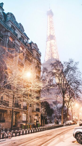 Snow covered trees and classic architecture near Eiffel Tower in France on a winter evening