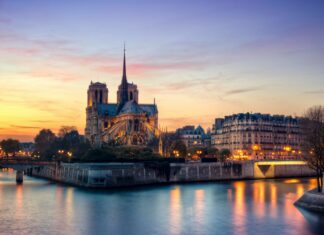 Notre Dame Cathedral stands majestically along the riverbank in France at sunset