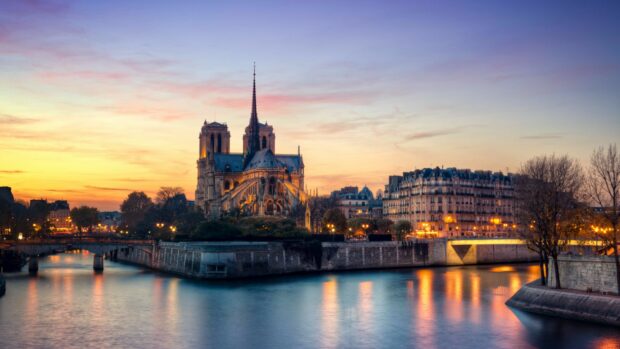 Notre Dame Cathedral stands majestically along the riverbank in France at sunset