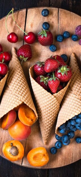A variety of berries including strawberries blueberries and cherries arranged in waffle cones on a wooden board, HD Phone Wallpaper