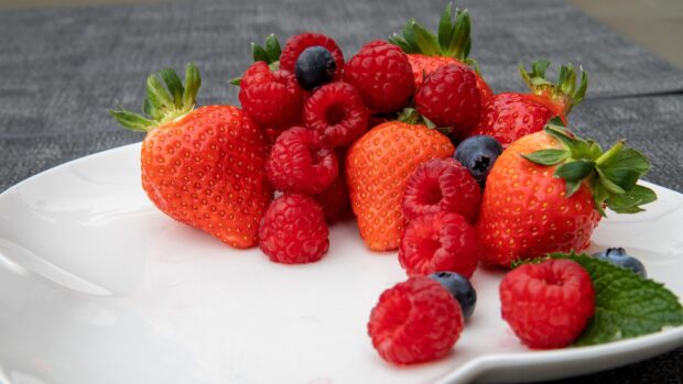 A close up of fresh berries including strawberries, raspberries, and blueberries on a plate, 4K Desktop Wallpaper
