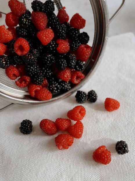 A bowl of fresh red and black berries spilled on a white cloth with detailed texture, HD Mobile Wallpaper