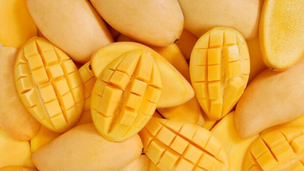 Fresh ripe mangoes with sliced cubes on a pile of yellow mangoes in a close up view, HD Desktop Wallpaper