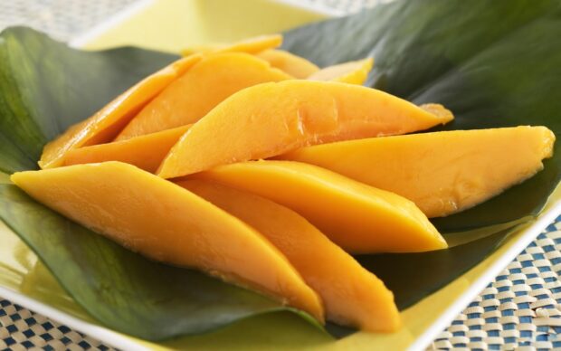 Fresh sliced mango is arranged neatly on large green leaves, HD Desktop Wallpaper