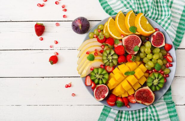 A vibrant fruit bowl with mango slices and assorted fruits on a white wooden table, HD Desktop Wallpaper