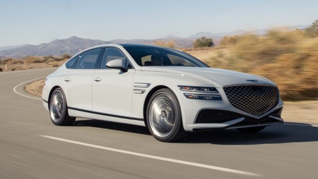 A white Genesis car is driving swiftly on an open road with mountains in the background, HD Desktop Wallpaper