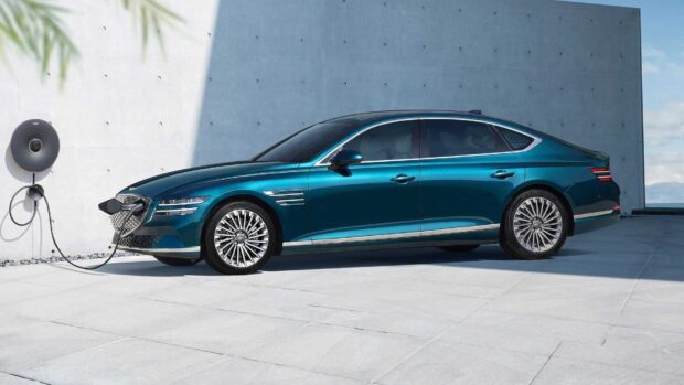 A Genesis car is charging with an electric cable attached to a wall charger outdoors, HD Desktop Wallpaper