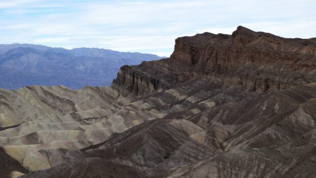 Geological formations with layered sedimentary rock patterns under a blue sky