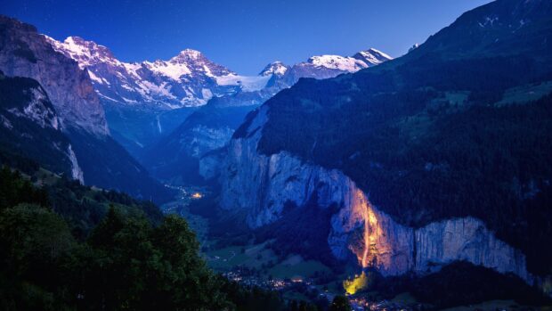 Majestic geology formations with illuminated waterfall in mountainous valley at dusk
