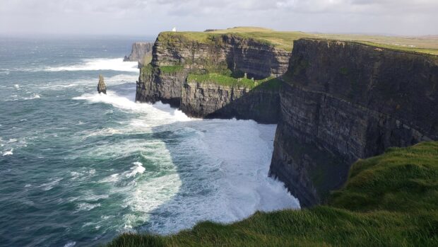 Rocky cliffs with layered geological formations overlooking the ocean waves crashing against the shore