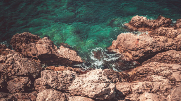 Rocky coastline geology with clear turquoise water and textured stone formations