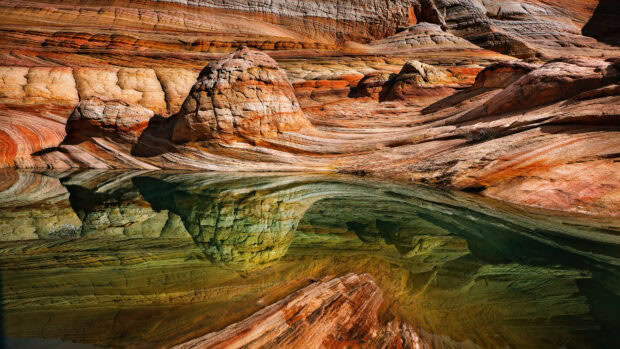 Stunning geology with colorful layered rock formations reflected in clear water