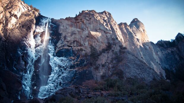 Tall cliff geology with frozen waterfall in winter landscape