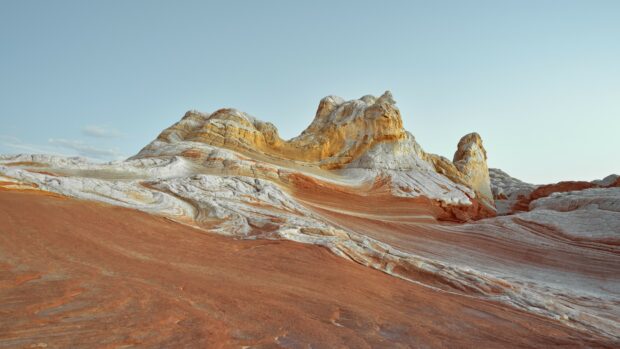 Unique geological formation with layered sedimentary rock and colorful patterns under clear sky