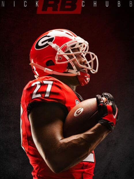 Football player in Georgia Bulldogs uniform holding ball against dark background