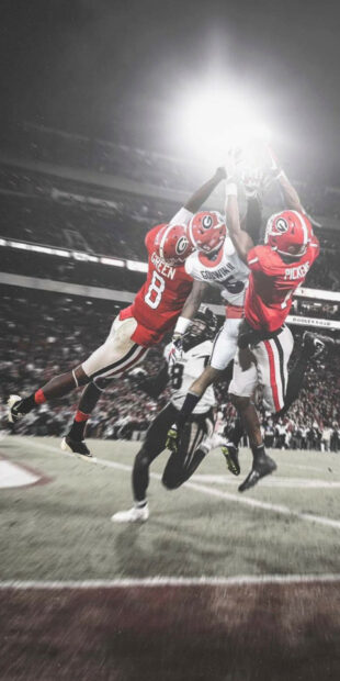 Georgia Bulldogs players jumping to catch the football in a competitive game action