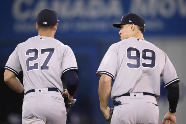 Giancarlo Stanton wearing number 99 standing beside a teammate on the baseball field