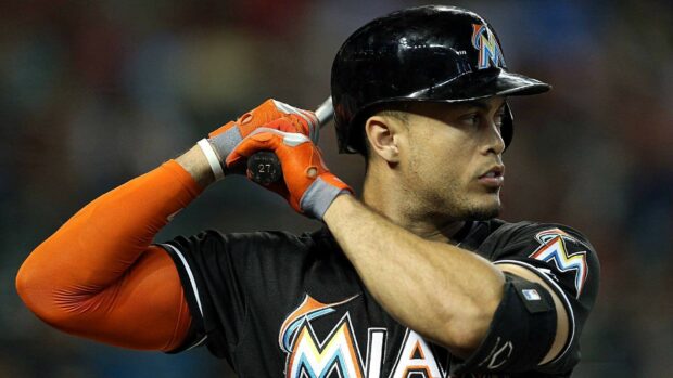 Giancarlo Stanton preparing to bat in a black Miami Marlins uniform with orange sleeves
