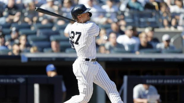 Giancarlo Stanton swinging a baseball bat in a pinstripe uniform during a game