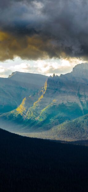 The image shows dramatic clouds over Glacier National Park mountains and forests, HD Phone Wallpaper
