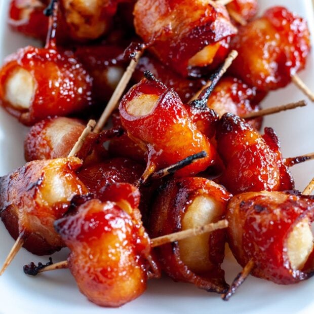 Glazed bacon wrapped chestnuts are arranged closely on a white plate, HD Desktop Wallpaper
