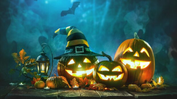 Three glowing Halloween pumpkins with autumn leaves and candles create a spooky scene, 4K Desktop Wallpaper