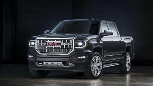 A black GMC truck is shown from the front with its headlights on, 2K Desktop Wallpaper